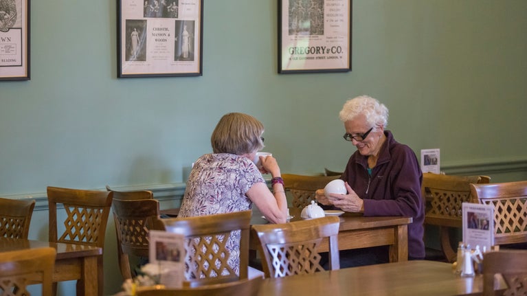 Two visitors sitting eating at a table in the café at Upton House and Gardens, Warwickshire.